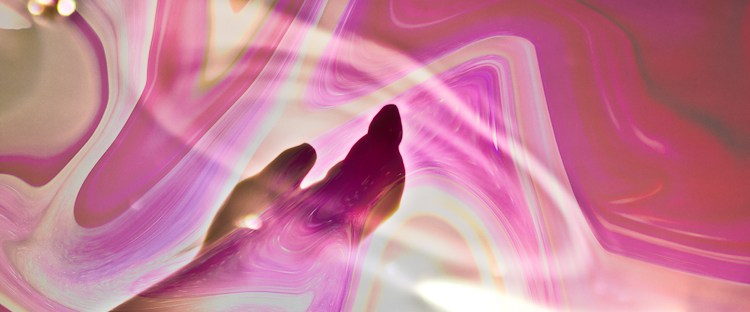surreal emerging hand from water and colored fluid pink and red background